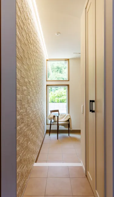 玄関ホール。石目調アクセント壁と高窓・地窓の採光